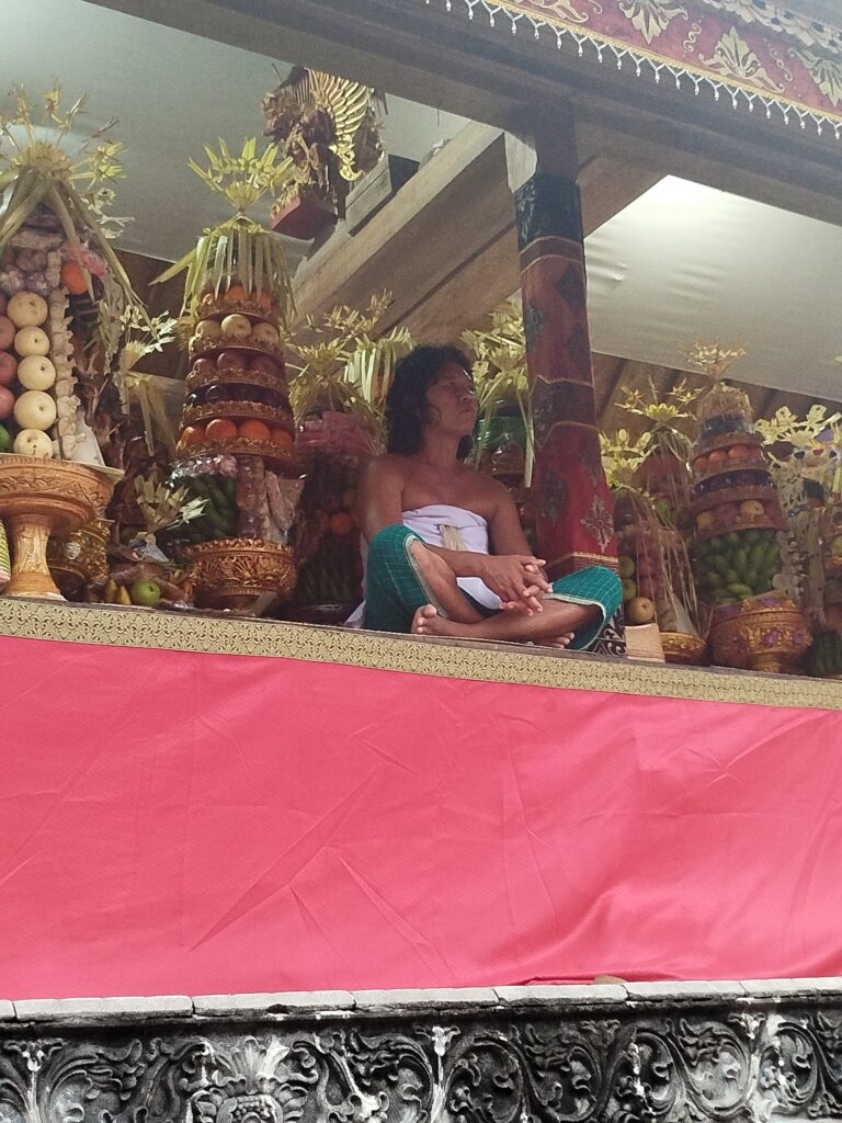 iMAGEN DE UN JOVEN PROTEGIENDO LAS OFRENDAS EN UNA CEREMONIA BALINESA
